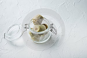 Artichoke hearts marinated in olive oil, on white textured background with space for text