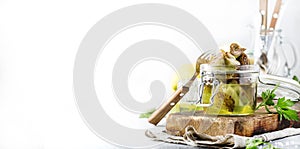 Artichokes in olive oil in jar with lemon and herbs on gray kitchen table background, selective focus