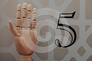 Articulated wooden hand with five fingers raised in allusion to number five