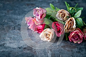 Artificial antique roses on stony background.