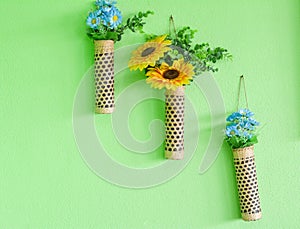 Artificial blue and yellow flower in bamboo pot hang on green wall. Copy space for your text