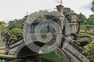 An artificial bridge with four statues of dragons with twisted tails, Tirta Gangga park, Karangasem region of Bali