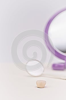 Dentistry mirror and ceramic dental crown on a white desk with space for text