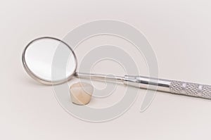 Mirror and ceramic dental crown on a white desk with space for text