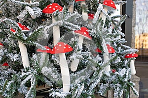 Artificial eco Christmas tree decorated with mushrooms with a red speckled hat with white snow. Decorations on the Christmas tree
