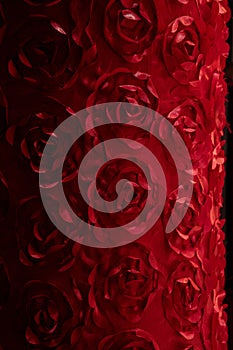 Artificial fabric rose flower texture closeup. Red floral backdrop with swirl rose shape pattern made from red fabric