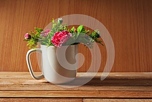 Artificial flower in cup on wooden