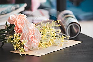 Artificial Flowers on black laptop desk with magazines background. selective focus