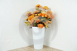 Artificial flowers bouquet in metal vase on wooden table interior decoration