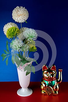 Artificial Flowers in a Porcelain Vase with Gold Coloured Maneki Neko Waving Lucky Cat