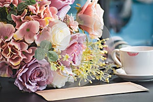 Artificial Flowers white ceramic cup of coffee with lipstick traces on black laptop desk background. selective focus