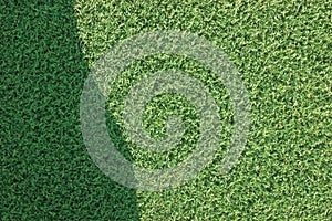 Artificial grass fake turf synthetic lawn field macro closeup, gentle shaded shadow area, green sports astroturf texture,