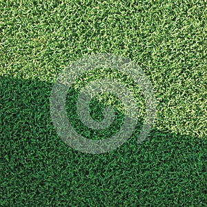 Artificial grass fake turf synthetic lawn field macro closeup, gentle shaded shadow area, green sports astroturf texture photo