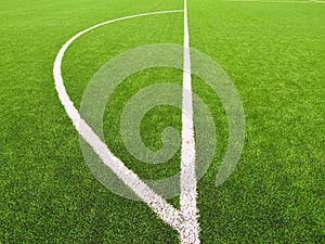 Artificial grass field on football playground. Detail of a cross of lines in a soccer field. Plastic grass and ground rubber