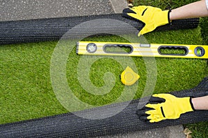 Artificial grass roll and tools in female hands.