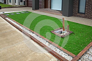 Artificial grass or synthetic lawn turf with timber garden edging in a landscaped front yard garden of an Australian home.