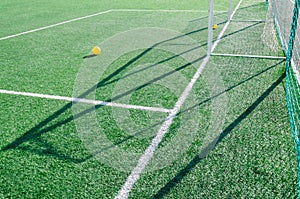 Artificial grass, white lines and soccer goal on a sunny day. Yellow balls on the grass