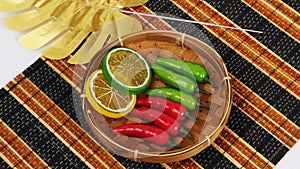 Artificial green chili red chili lime yellow leaf in the basket on traditional mat studio photo