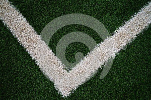 Artificial green grass with a V shaped white line that is slightly routed to the left at the bottom