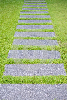 Artificial green grass walk way with concrete plate background