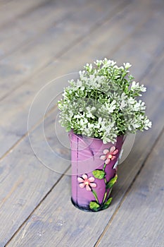 Artificial green seedling in a small pink bucket against a dark background