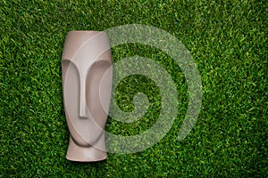 Artificial head lying on green grass