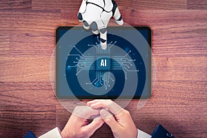 Artificial intelligence concept with robotic hand pointing at tablet