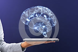 Artificial intelligence and machine learning concept with digital glowing human brain symbol above digital tablet on woman palm on