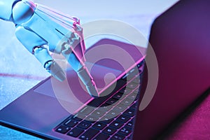 Artificial intelligence. Robot hand using laptop on table in neon lights, closeup