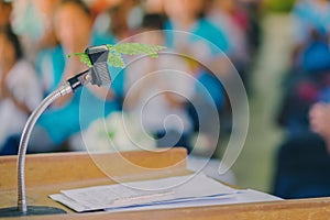 Artificial leaf inserted in the desktop microphone stand on podium in the auditorium