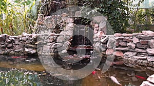 Artificial man made waterfall waterscape with koi fish in pond