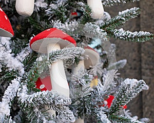 Artificial mushroom Amanita decorates a Christmas tree. Amanita with a red hat close-up. Snow-covered branches of