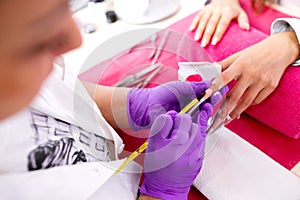 Artificial nail enhancement being applied by the hands of an experienced manicure salon worker