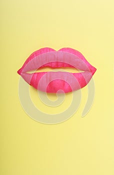 Artificial pink lips on yellow background.