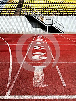 Artificial red autumn treadmill with numbers, running track in the old stadium. Flat background, top view