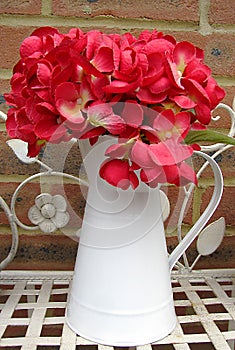 Artificial red hydrangea in white jug