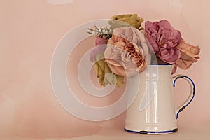 Artificial roses in a ceramic white pitcher