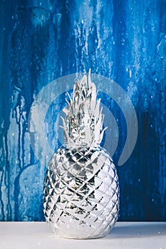 Artificial silver pineapple on blue painted wall background