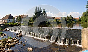 Artificial sluice and village on the Otava river, splashing water frozen, beauty of czech