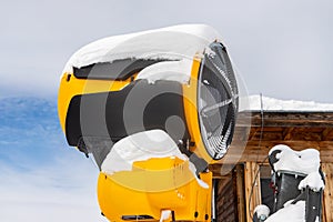 Artificial Snow cannon near piste.Ski lift ropeway on hilghland alpine mountain winter resort on bright sunny day. panoramic wide