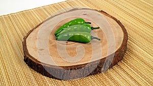 Artificial three green chili on the wood and brown paddy stalk mat studio photo
