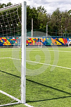 Artificial turf on the football field. Part of the football goal and green synthetic grass on the sports field on the background