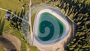 Artificial water catchment reservoir for snow skiing slopes at Dolomites, Italy