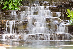 Artificial water fall in the garden. artificial pond with a waterfall in a landscape design. A small artificial waterfall surround