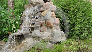 An artificial waterfall created by human hands. Water flows down the stones into the pond, landscaping. Background for