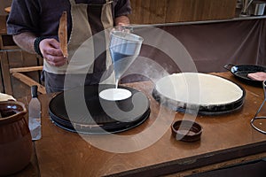 Baker`s hands pouring sweet on the griddle for the sweet crepe`s preparations photo