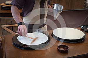 Baker`s hands pouring sweet on the griddle for the sweet crepe`s preparations photo