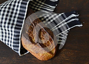 Artisan Bread Loaf Wrapped in a Black and White Cloth on a Wooden Table Top-Down View