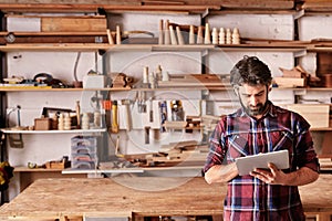 Artisan carpenter in his woodwork studio using digital tablet