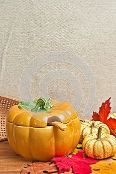 Artisan ceramic pumpkin soup bowl with fall leaves on wood board